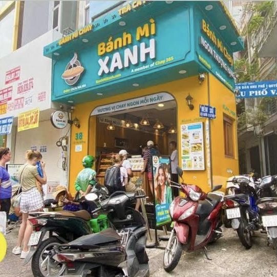 Mặt tiền cửa hàng Bánh Mì Xanh - chuỗi bánh mì chay nhượng quyền với biển hiệu cyan và mustard signature